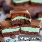 Refreshing Mint Chocolate Brownies 6 three mint brownies stacked in a pyramid. top brownie has bite taken out of it. more brownies can be seen in the background.
