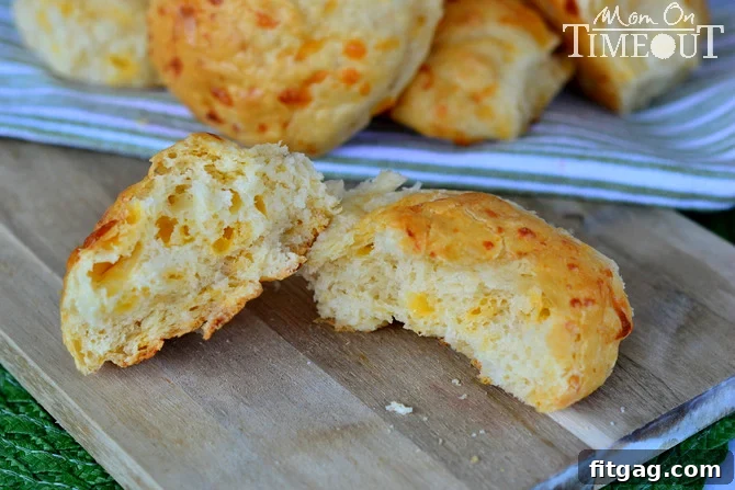 Easy No-Knead Cheddar Rolls | MomOnTimeout.com Close-up of golden brown easy no-knead cheddar rolls on a wooden board.