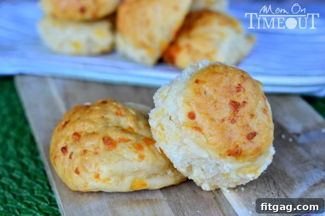Easy No-Knead Cheddar Rolls | MomOnTimeout.com A baking sheet filled with no-knead cheddar rolls, some brushed with egg wash.