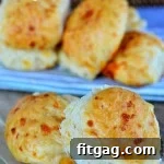 Easy cheddar rolls recipe sitting on wood board with more rolls in background