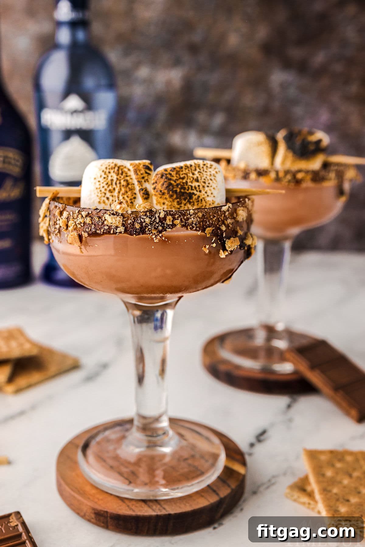 Two Smores martini with toasted marshmallow garnish and chocolate and graham cracker rim sitting on coasters ready to be enjoyed.