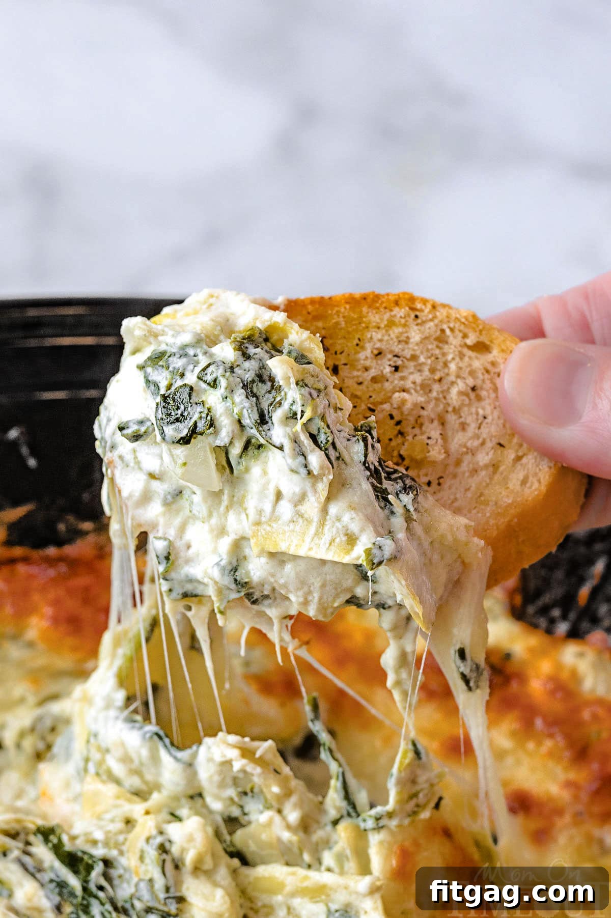 One Pot Wonder Spinach Artichoke Dip 6 Golden crostini being dipped into the rich, creamy crockpot spinach artichoke dip, showcasing its enticing texture.