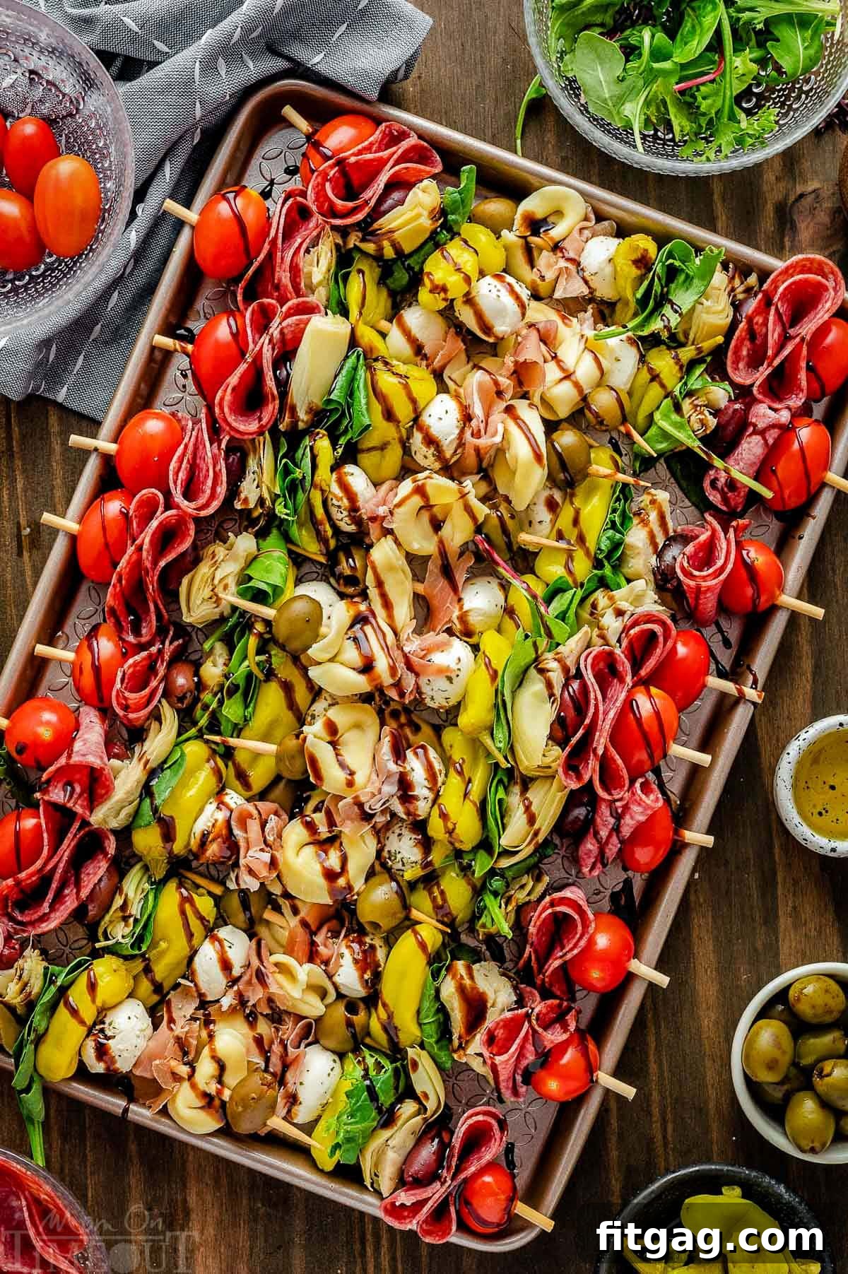 Top down view of antipasto skewers on a sheet pan drizzled with balsamic glaze and ready to eat, showcasing a colorful array of ingredients.
