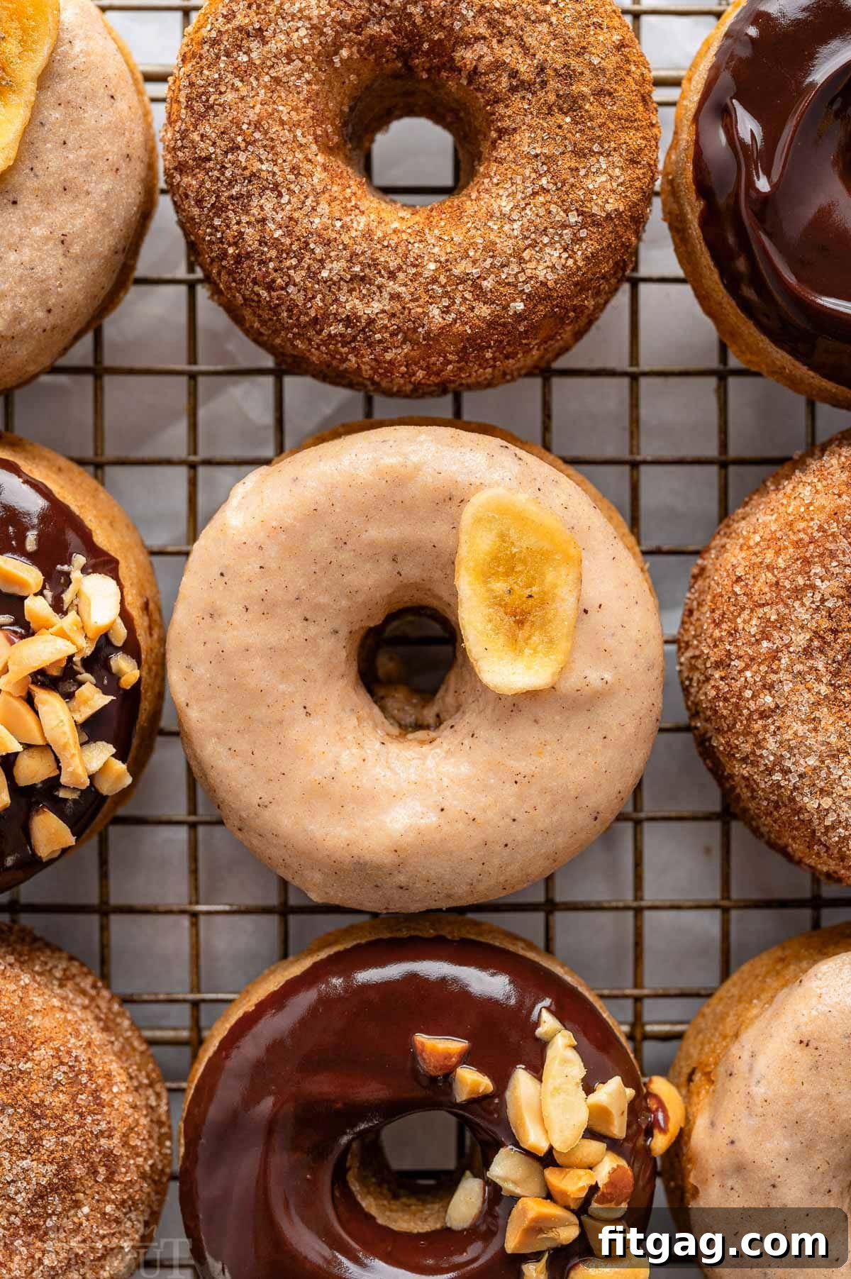 Banana Bliss Donuts 2 A top down view of banana donuts with various toppings. The donuts are on a metal cooling rack.