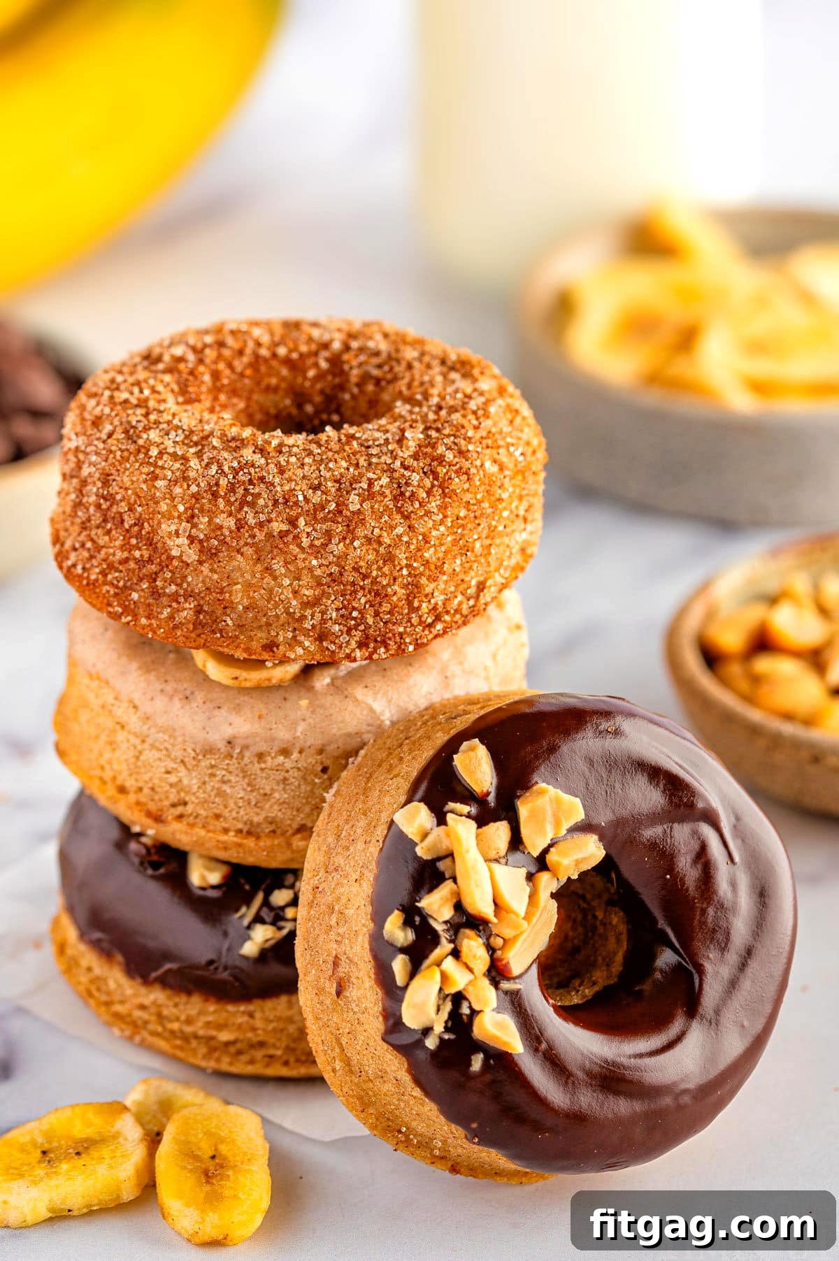 Banana Bliss Donuts 8 Stack of banana donuts with a chocolate glazed donut leaning against the stack.