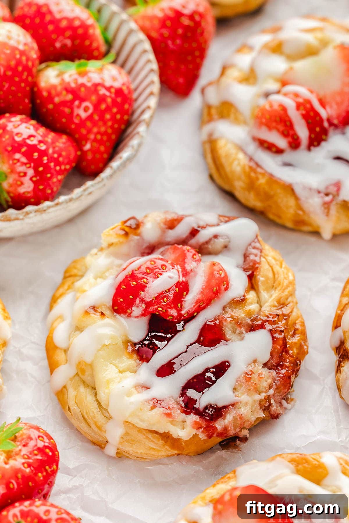 Strawberry Danish Delight 2 A perfectly baked Strawberry Danish, featuring a flaky pastry base, a visible creamy cream cheese center, topped with a sweet white glaze and slices of fresh, red strawberries.
