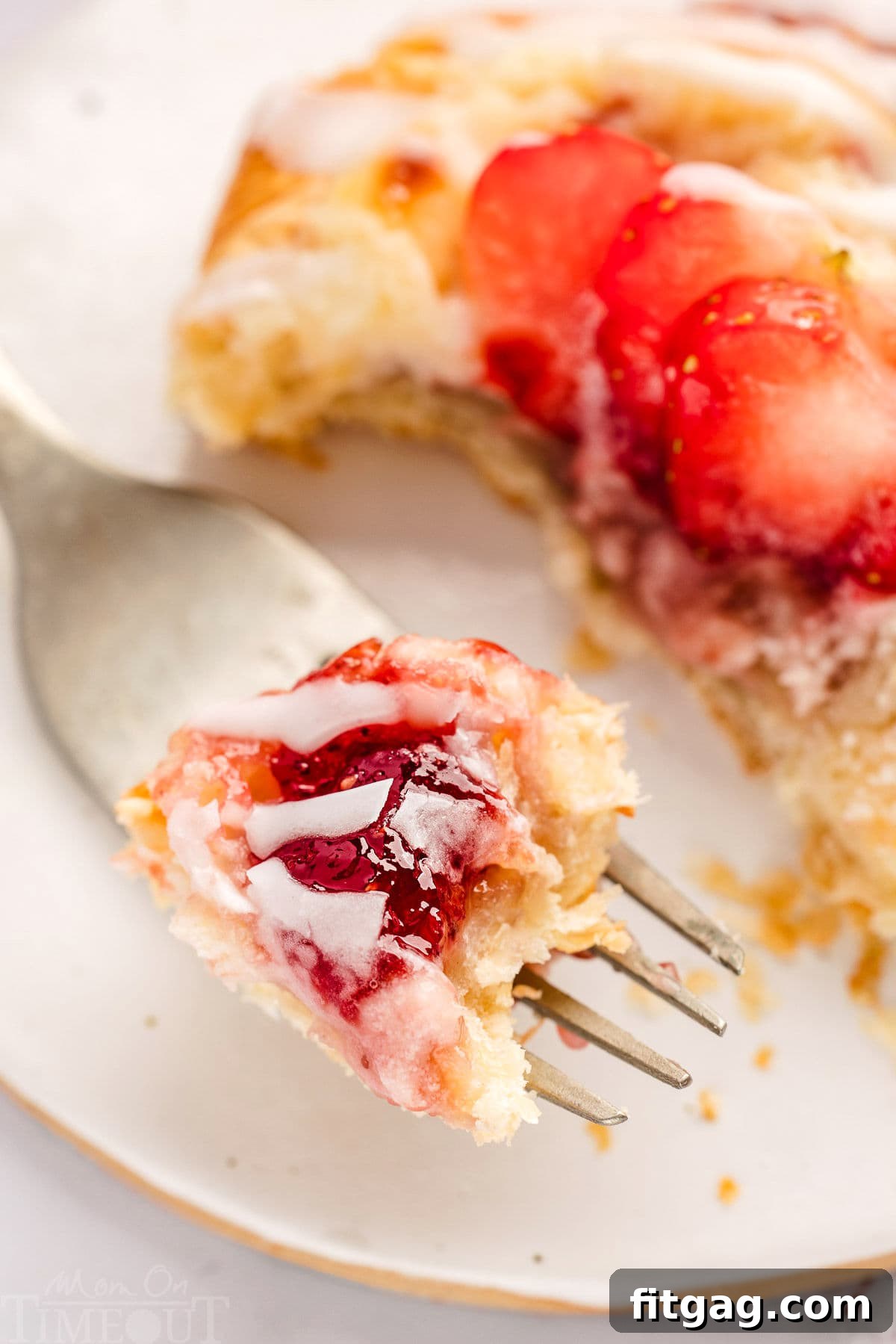 Strawberry Danish Delight 8 A single Strawberry Danish served on a white plate with a fork, showing a portion ready to be eaten, highlighting its flaky texture and rich filling.