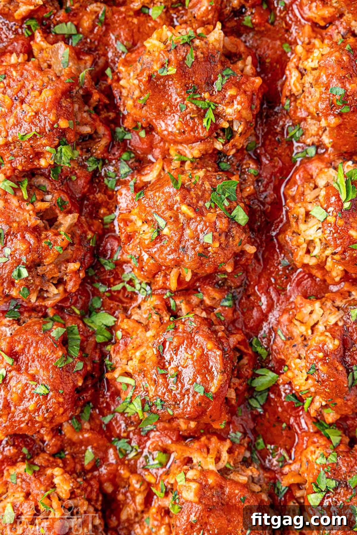 Rice Quilled Meatballs 7 Porcupine Meatballs with fresh parsley sprinkled on top. The meatballs are lined up in a baking pan.