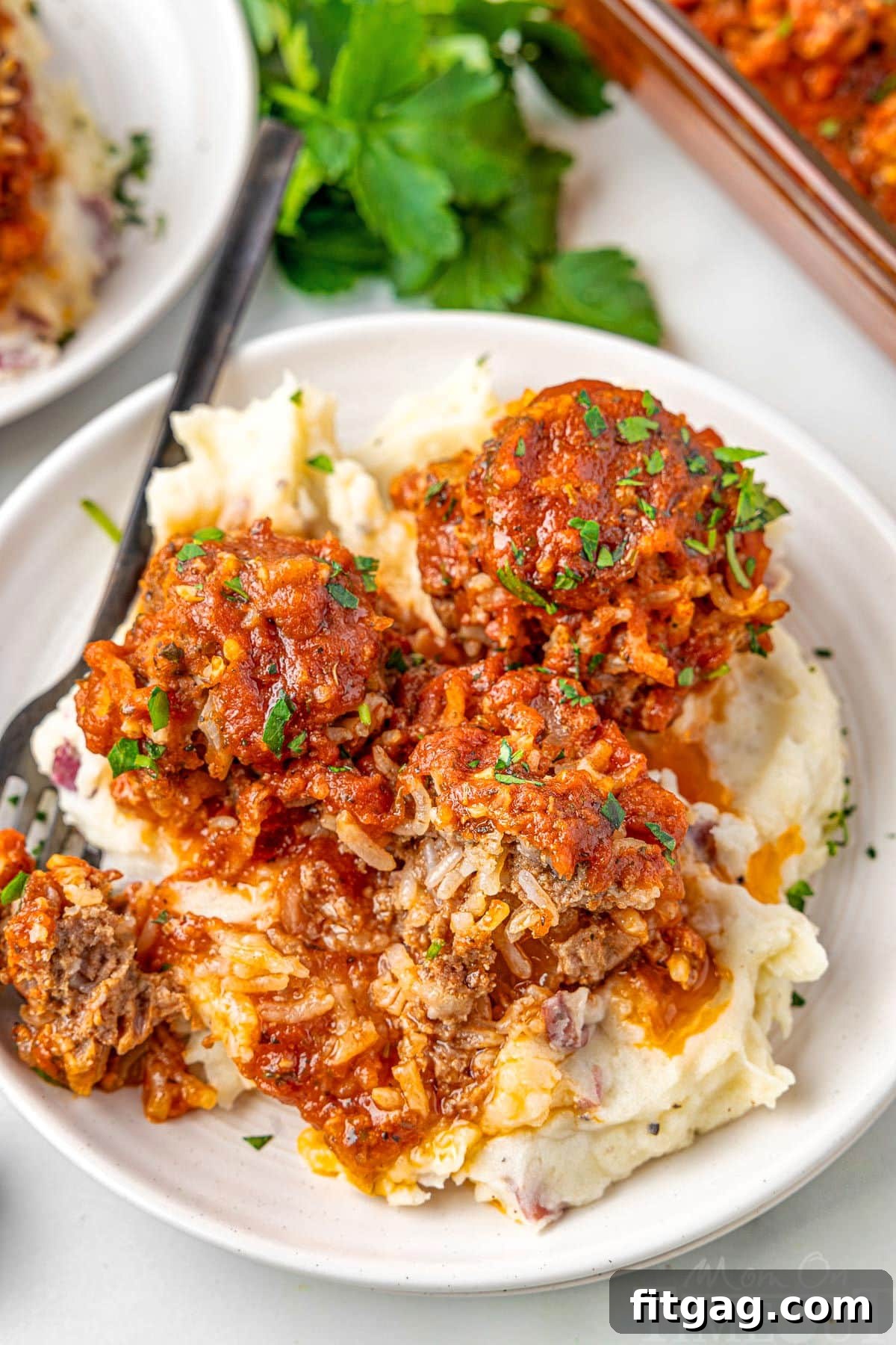 Rice Quilled Meatballs 8 3 meatballs on a bed of mashed potatoes on a white plate.