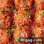 Porcupine Meatballs with fresh parsley sprinkled on top. The meatballs are lined up in a baking pan.
