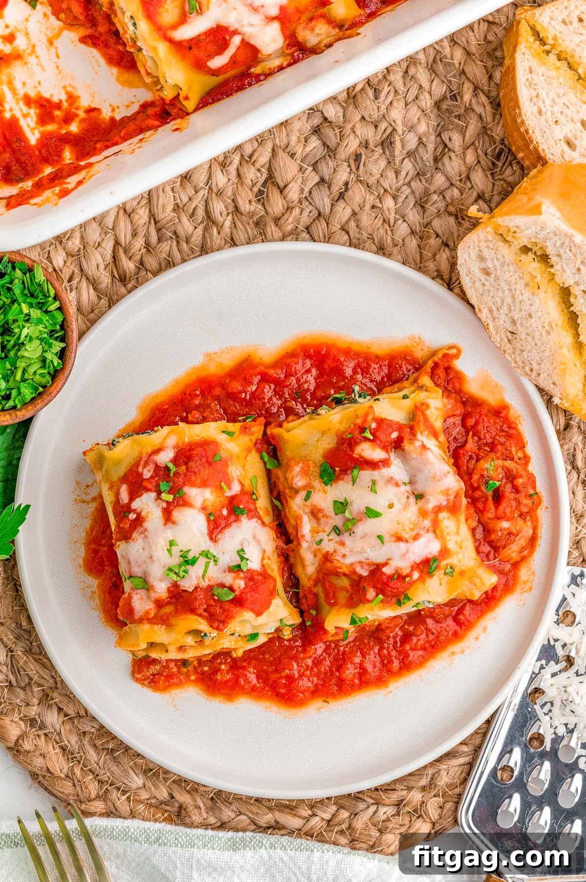 Lasagna Pinwheels 8 Top down look at two lasagna roll ups on a plate next to the casserole dish.