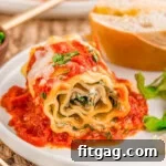 Lasagna Pinwheels 10 Lasagna Roll Ups plated with salad and bread on a dinner plate.