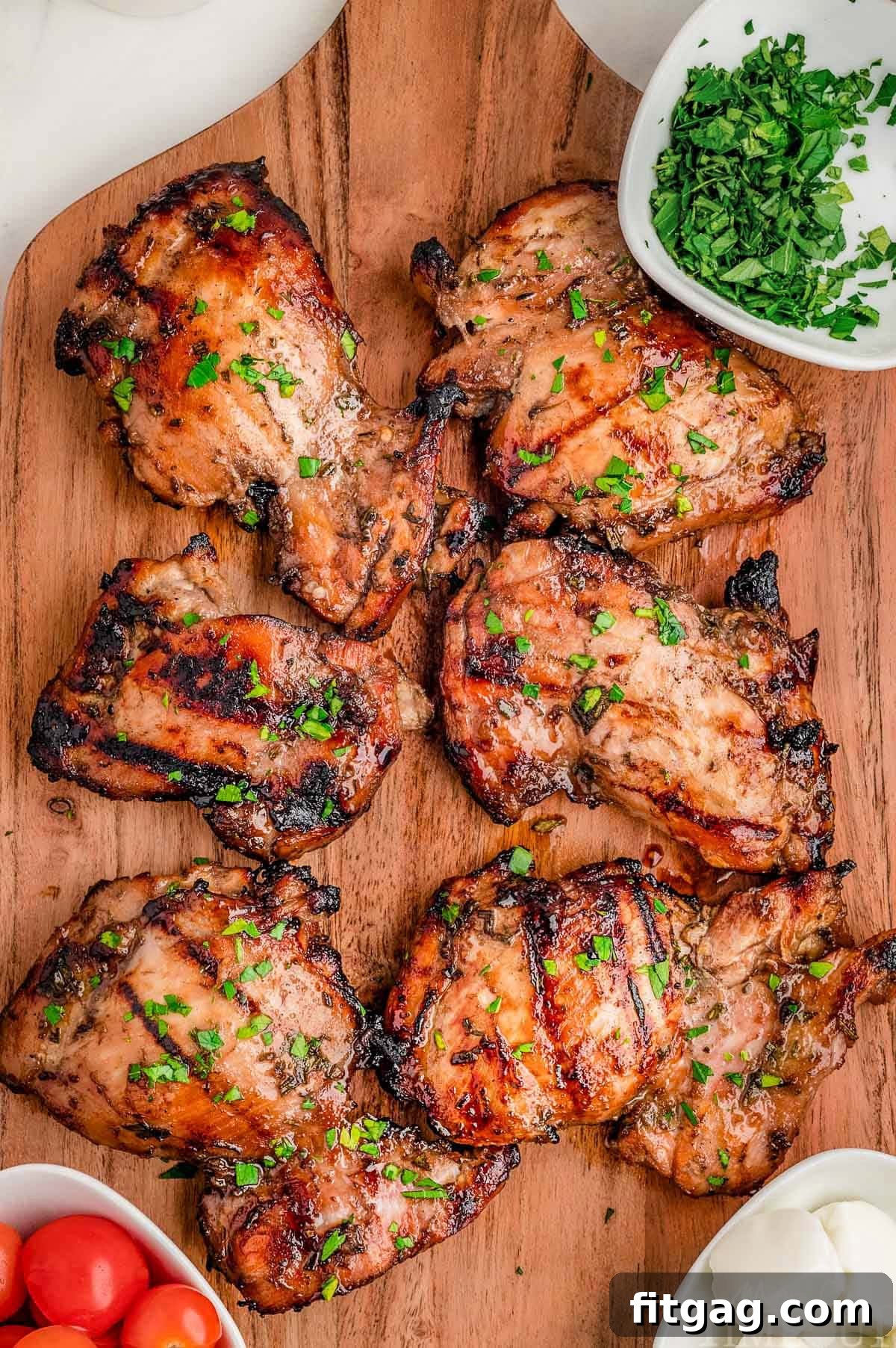 Overhead shot of six balsamic chicken thighs on wood cutting board grilled and ready to be served.