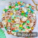 Top down view of Leprechaun Bait snack mix in white round bowl. Brass tongs are sitting next to the bowl.