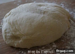 Gently removing perfectly risen pizza dough from the bread machine.
