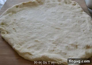 Shaping the bread machine pizza dough on a floured surface.