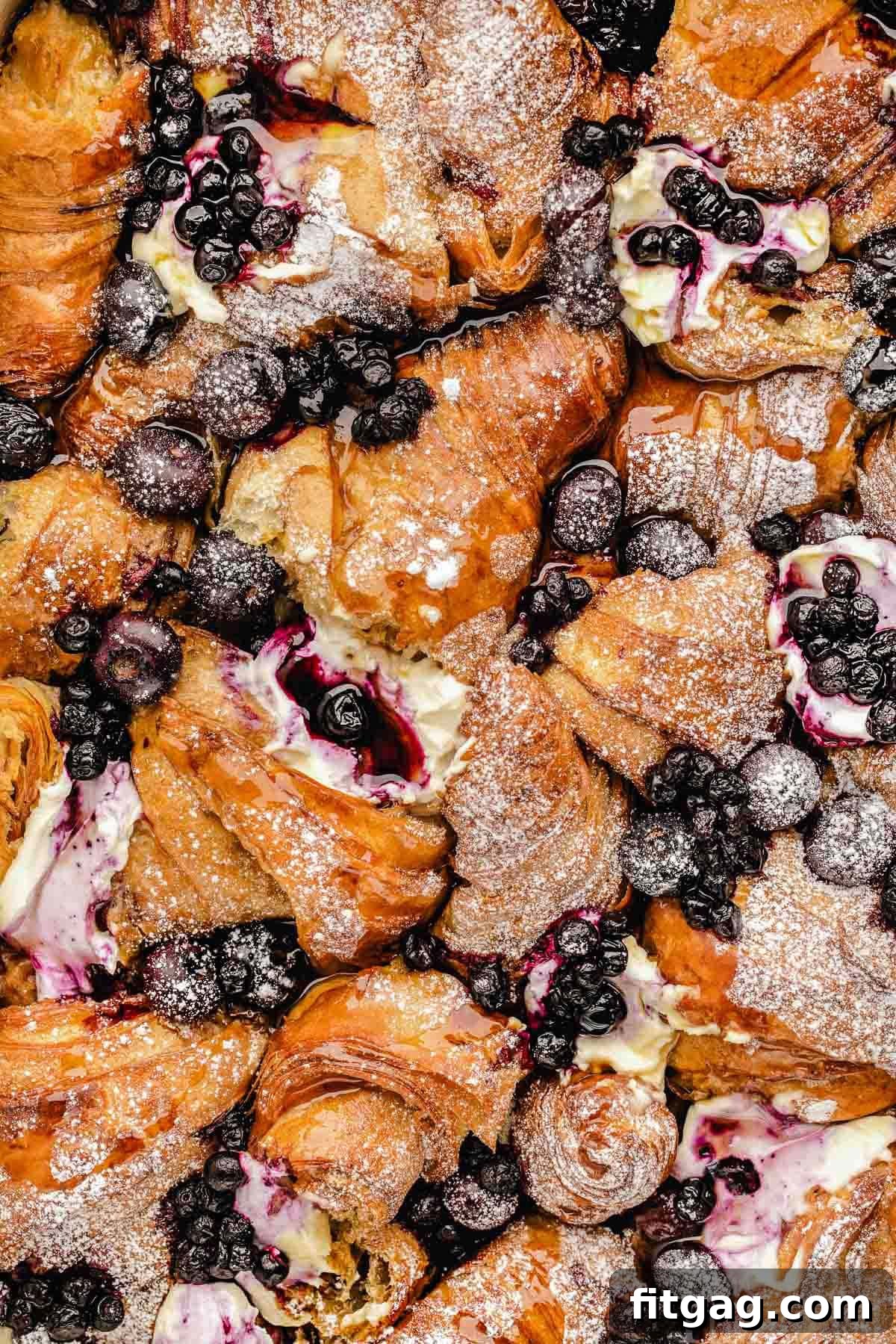 Close-up of baked blueberry croissant french toast in a baking dish, showcasing the golden-brown crust and juicy blueberries.