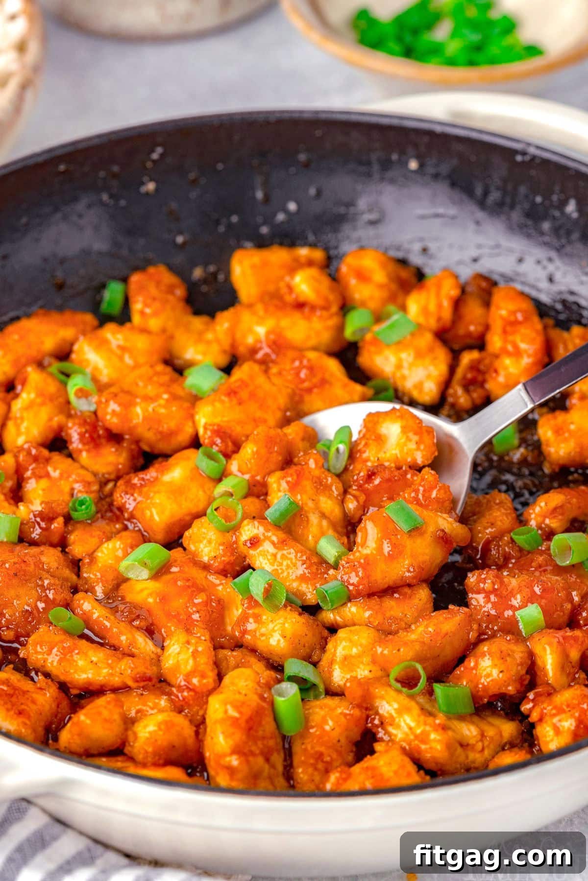 A robust cast-iron skillet filled with sizzling, glazed Firecracker Chicken, perfectly cooked and ready to be dished out.