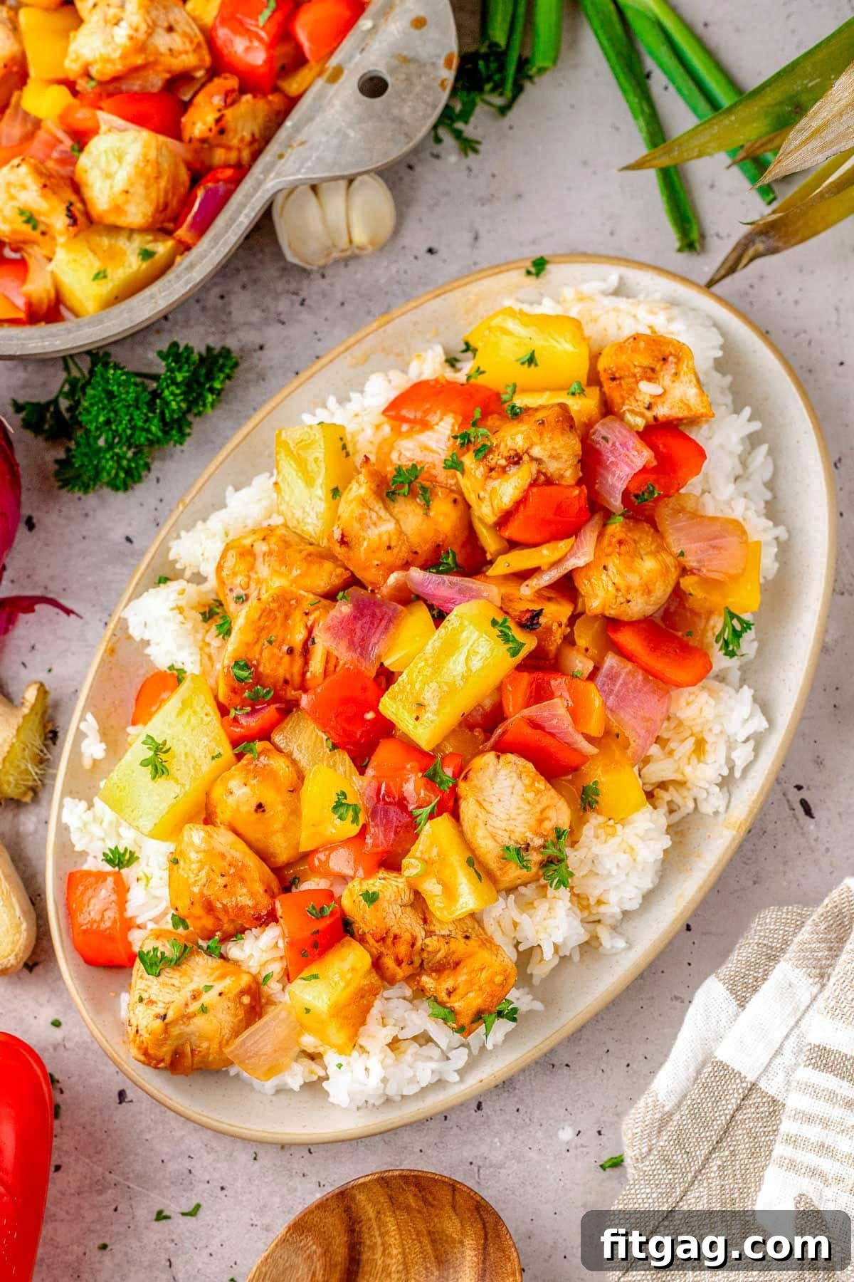 Hawaiian Chicken recipe plated with rice on an oval plate, garnished with green onions and sesame seeds.