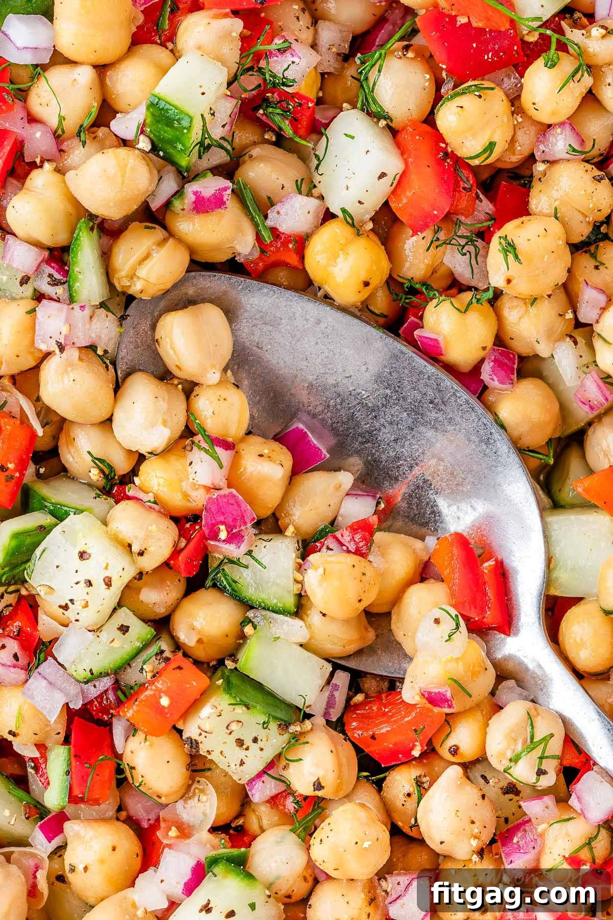 A close-up, overhead view of a vibrant garbanzo bean salad in a large white bowl, showcasing the fresh ingredients.
