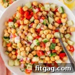 Bowl of chickpea salad recipe being held up over two small plates with the salad on them.