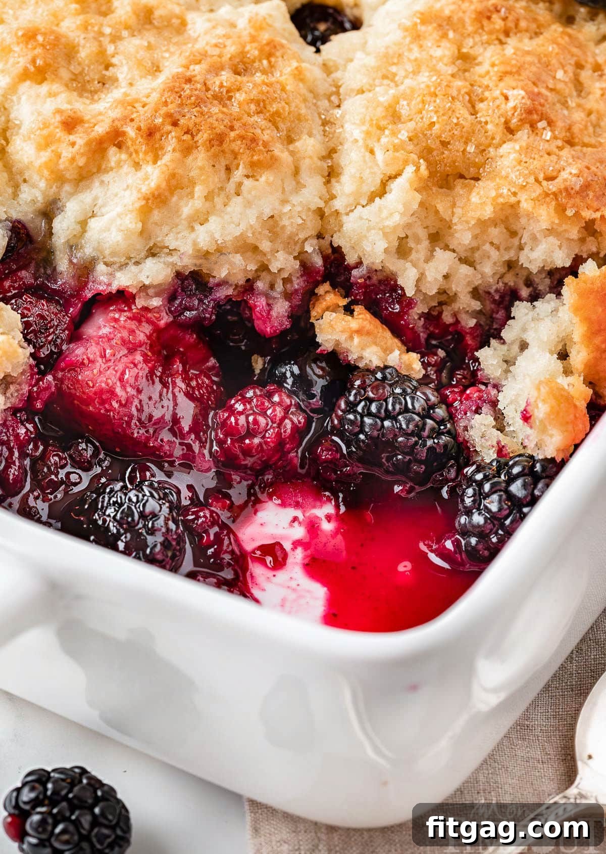 Sweet Berry Indulgence 3 Angled view of berry cobbler recipe in white baking dish showing the mixed berries and biscuit topping.