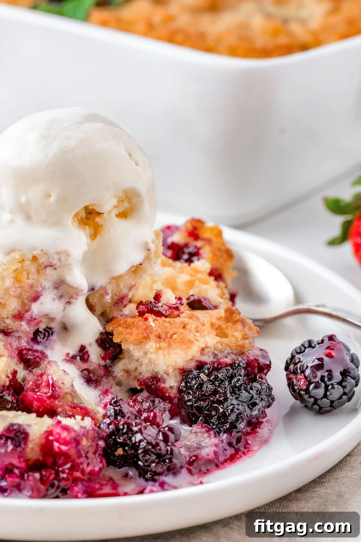 Sweet Berry Indulgence 7 Easy berry cobbler recipe on white round plate with vanilla ice cream and a spoon.
