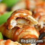 A sliced caramel apple empanada revealing the apple and caramel filling, with others on a plate.