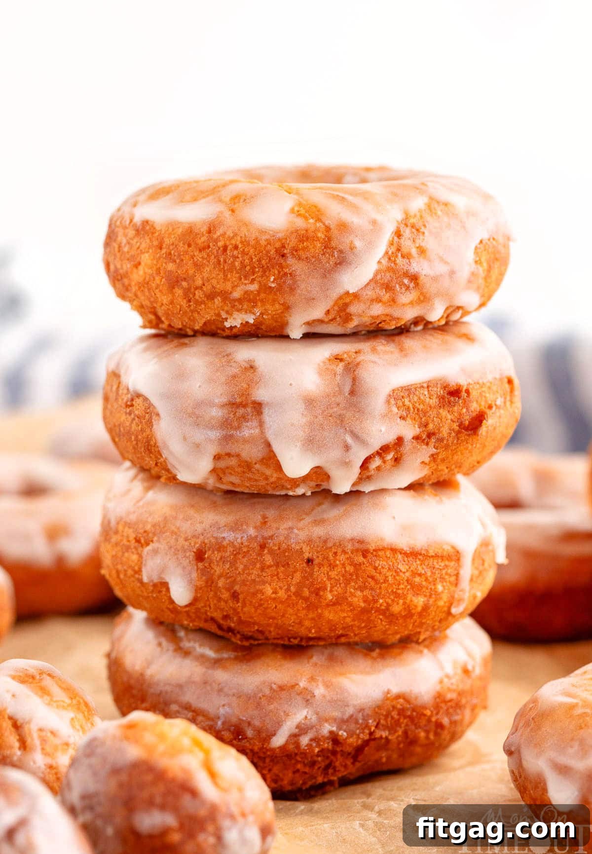 Stack four tall of glazed cake donuts on brown parchment paper.