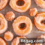 Overhead shot of sour cream cake donut on wire rack topped with glaze.