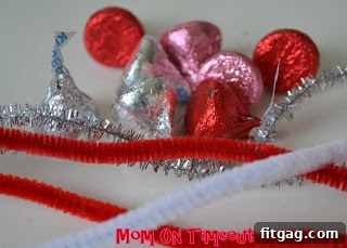 Two pipe cleaners twisted into an X shape, forming the base for the Hershey's Kiss ring.