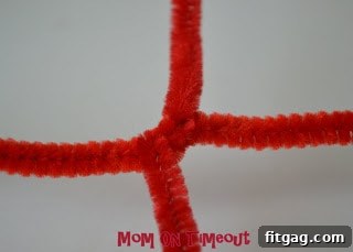 A Hershey's Kiss candy placed securely in the center of the pipe cleaner X, ready to be wrapped.