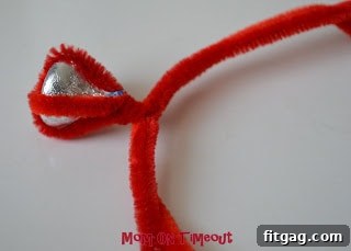 Bending the separated pipe cleaner ends around a finger to form the circular band of the ring.