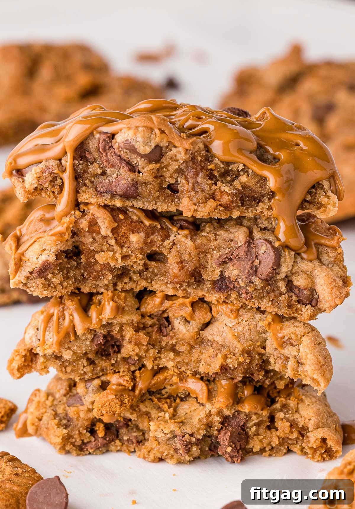 Golden Speculoos Chocolate Chip Dreams 3 A stack of four homemade Biscoff chocolate chip cookies, each generously drizzled with smooth cookie butter, presented on pristine white parchment paper.
