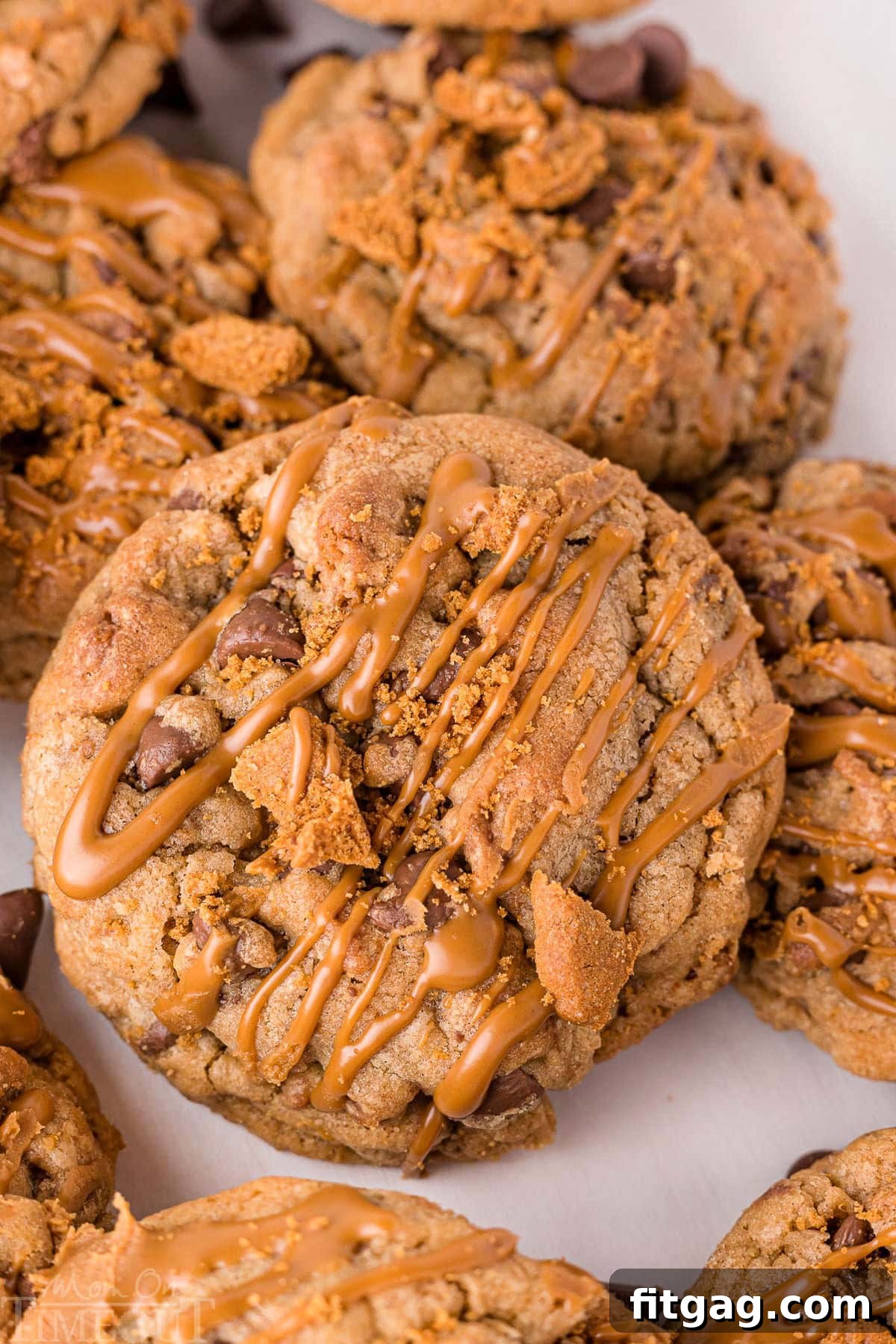 Golden Speculoos Chocolate Chip Dreams 4 A beautiful arrangement of about five Biscoff chocolate chip cookies, each adorned with a generous drizzle of melted cookie butter, highlighting their golden-brown edges and soft centers.
