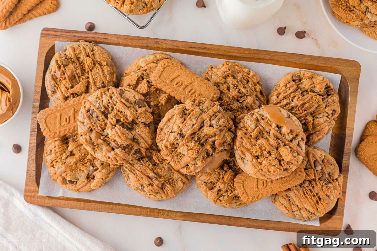 Golden Speculoos Chocolate Chip Dreams 7 A rustic wood tray overflowing with baked Biscoff cookie butter cookies and some whole Biscoff cookies, inviting a delicious tasting experience.