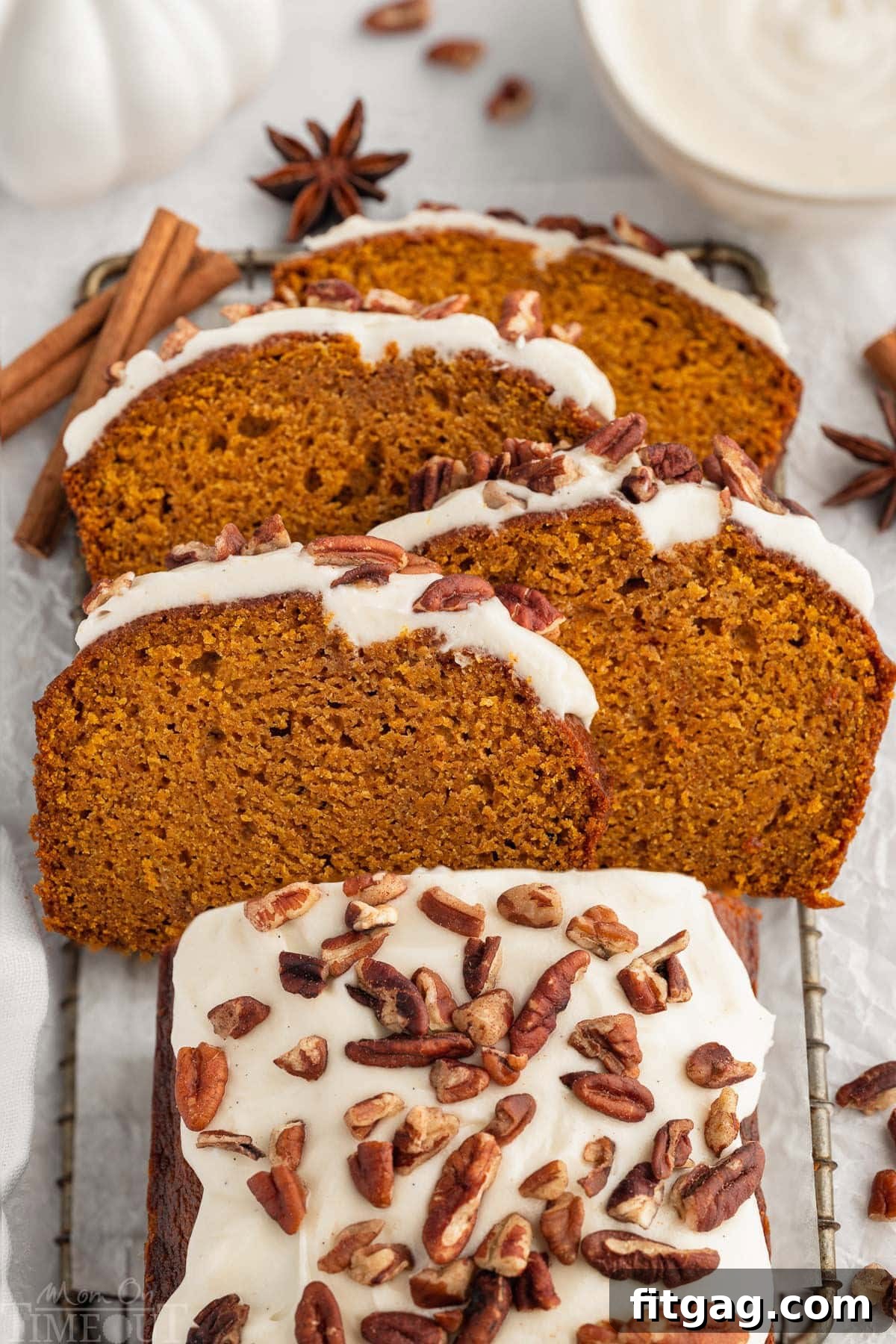 Overhead shot of pumpkin bread with cream cheese frosting on board with four slices cut and arranged on top of each other at an angle.