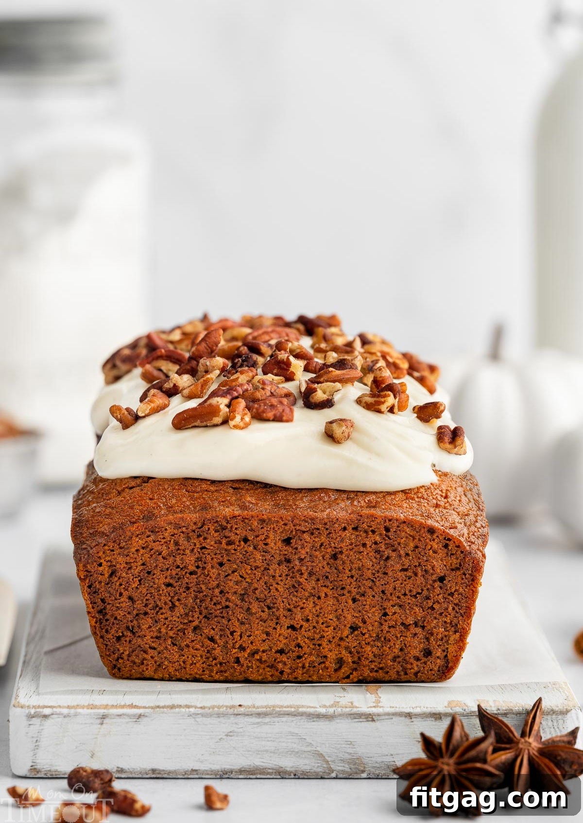 whole pumpkin loaf with cream cheese frosting sitting on white cutting board.