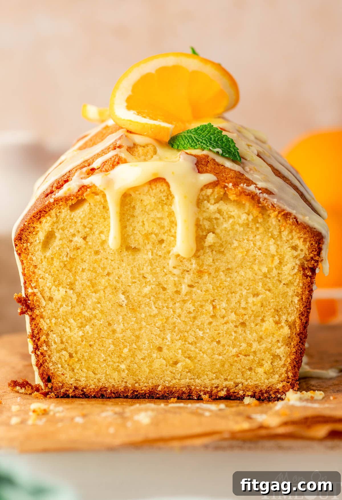 Bright Orange Loaf 2 Orange pound cake with end cut off sitting on wood board topped with a glaze.