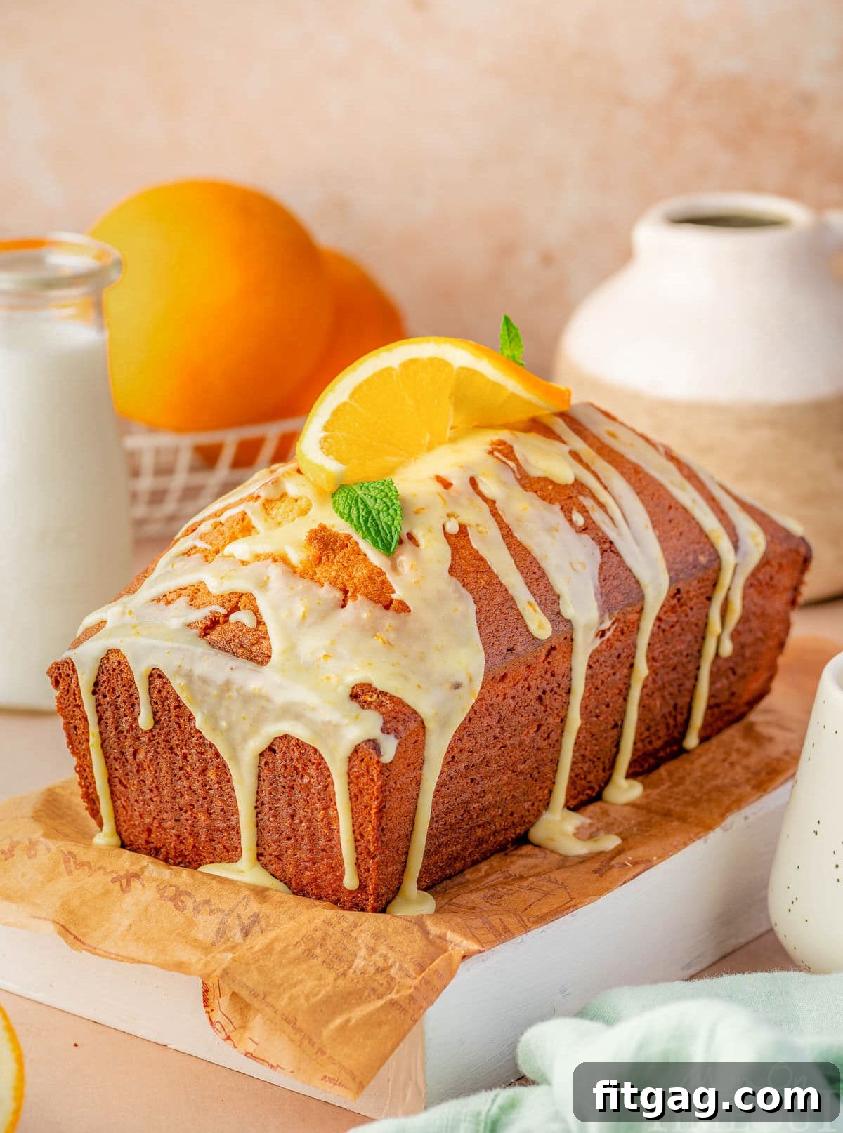 A beautifully baked whole Orange Pound Cake, perfectly glazed, resting on a rustic wooden cutting board, ready for serving.