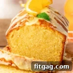 Front view of orange pound cake on wood cutting board with two slices cut off.