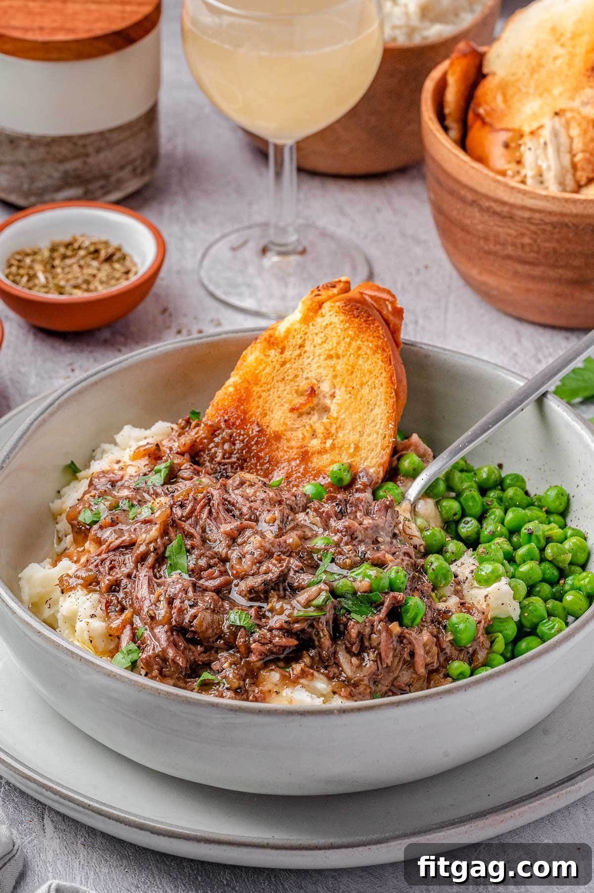 Slow-Cooked French Onion Beef 3 Bowl of french onion soup pot roast with mashed potatoes and peas and slices of baguette.