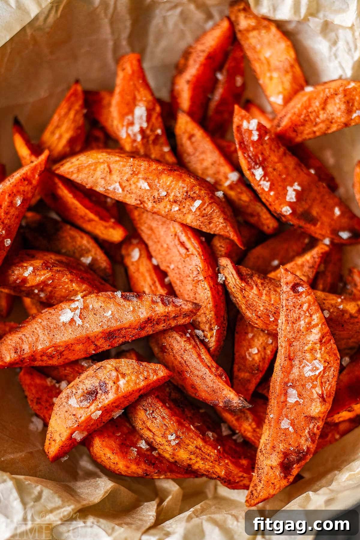 Close-up shot of sweet potato wedges lightly sprinkled with flaky sea salt, highlighting their golden-brown edges.