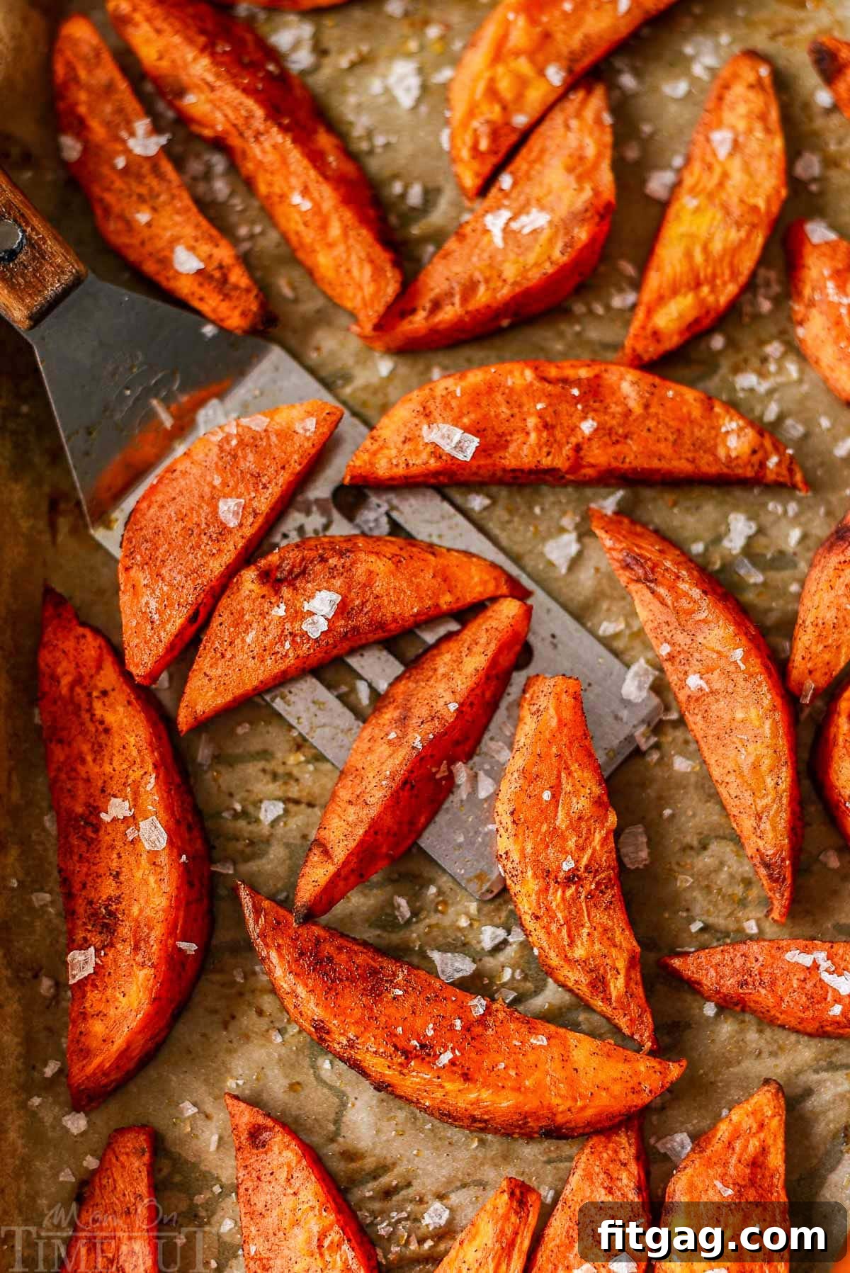 Top-down view of perfectly roasted sweet potato wedges in a single layer on a parchment-lined baking sheet, showcasing their crisp edges.