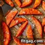 Top down look at roasted sweet potato wedges on parchment lined baking sheet.