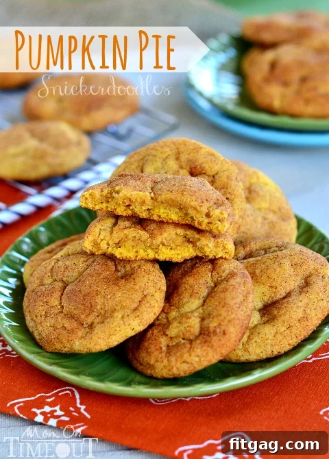 Pumpkin Pie Snickerdoodles displayed beautifully on a white plate, with one cookie cut in half revealing its soft, spiced interior.