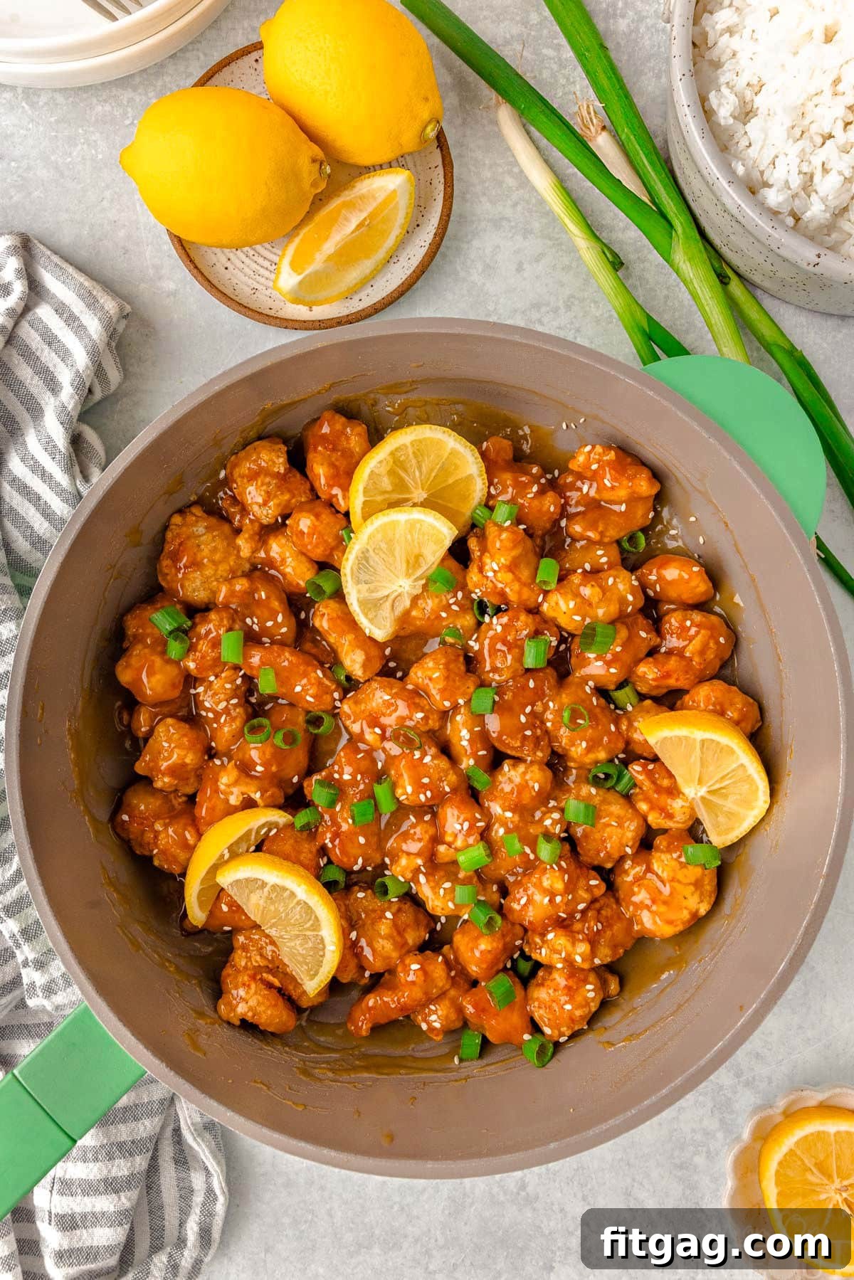 Golden Glazed Lemon Chicken 3 Overhead shot of skillet of chinese lemon chicken ready to be served. Garnished with slices of lemon and green onions.