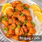 Golden Glazed Lemon Chicken 9 Overhead shot of lemon chicken and white rice on round plate with lime slices and green onions for garnish.