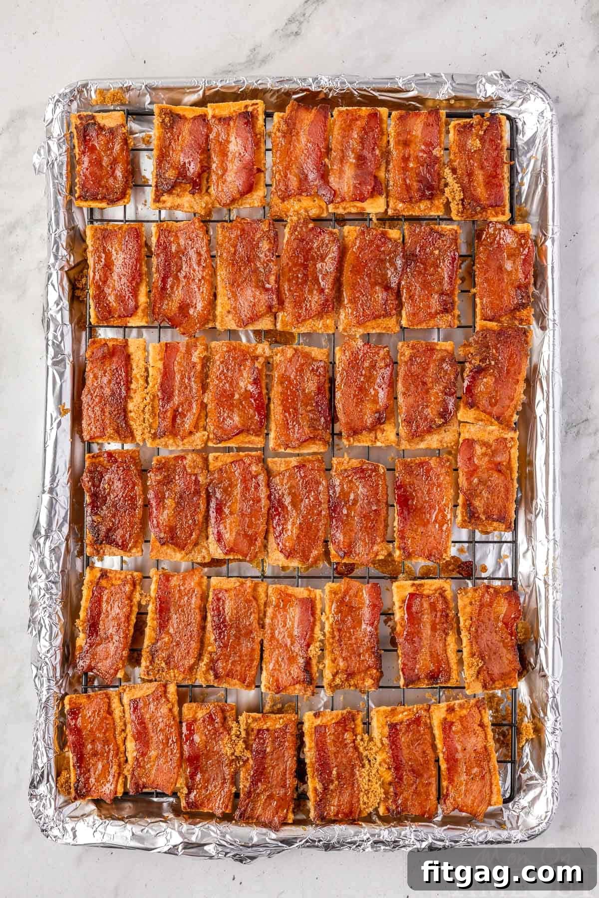 Overhead shot of candied bacon crackers arranged on a baking sheet with a cooling rack, freshly out of the oven.