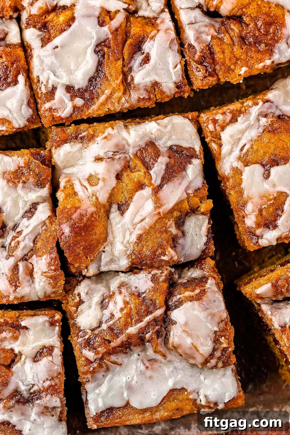 Overhead shot of pumpkin cinnamon focaccia cut into squares drizzled with glaze.